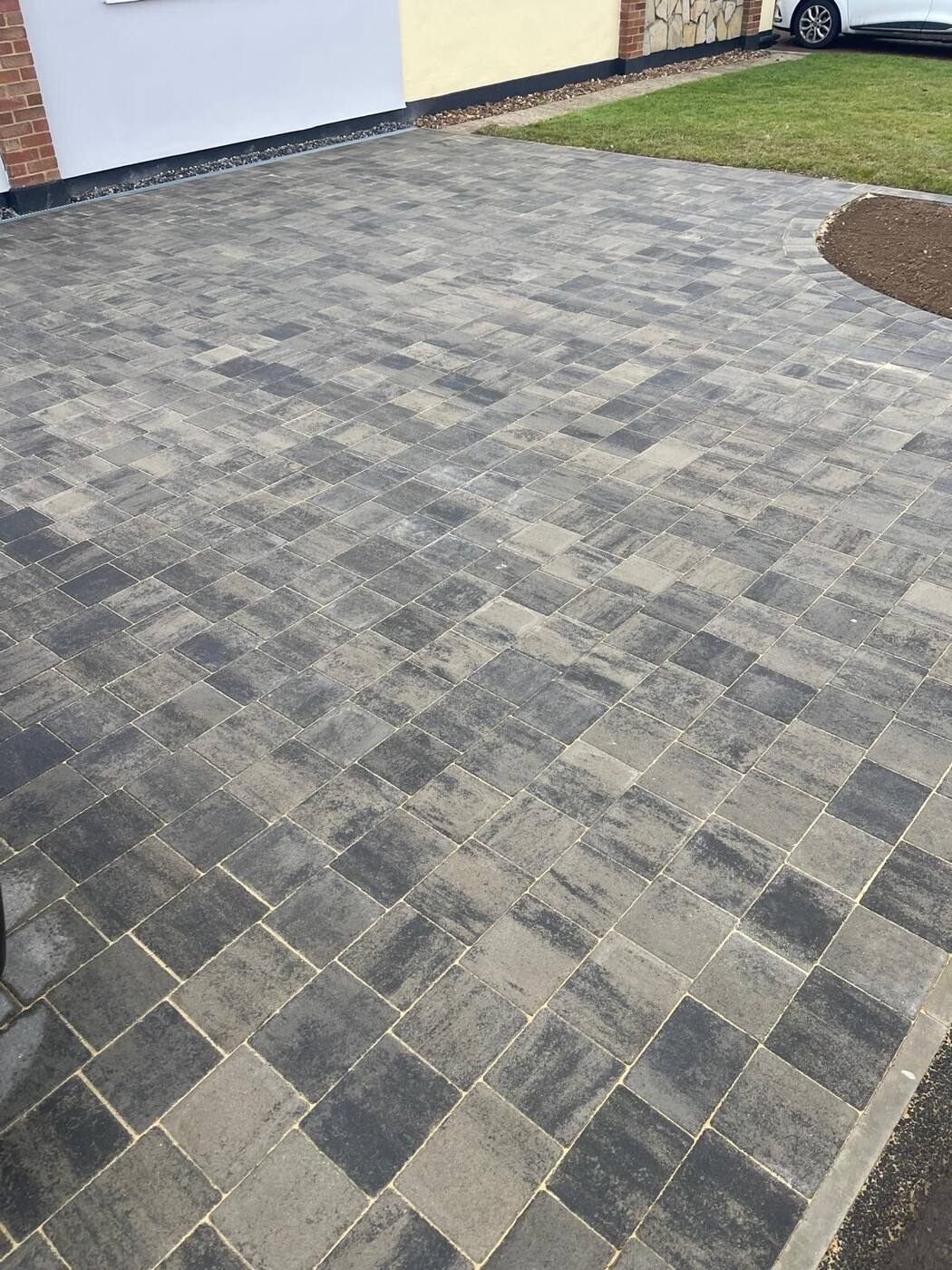 Block paving driveway, full view with house and lawn corner